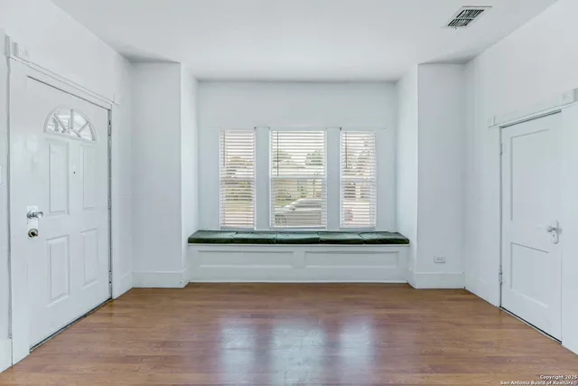 an empty room with wooden floor and windows