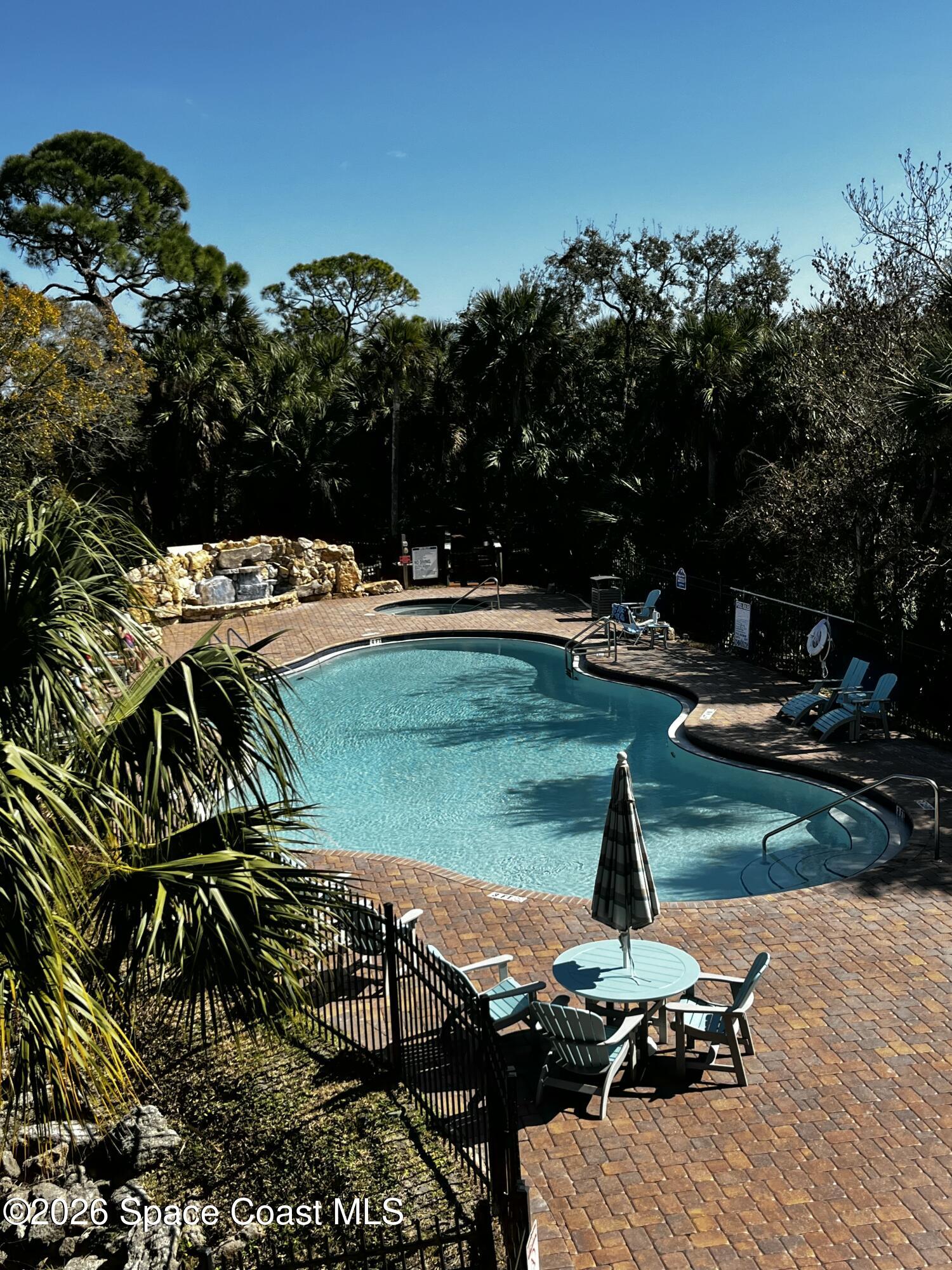 735 Pilot Lane, Unit 503 Merritt Island, FL 32952 - Photo 16 of 26 a view of a swimming pool with lawn chairs under an umbrella