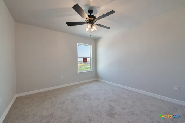 an empty room with window and ceiling fan