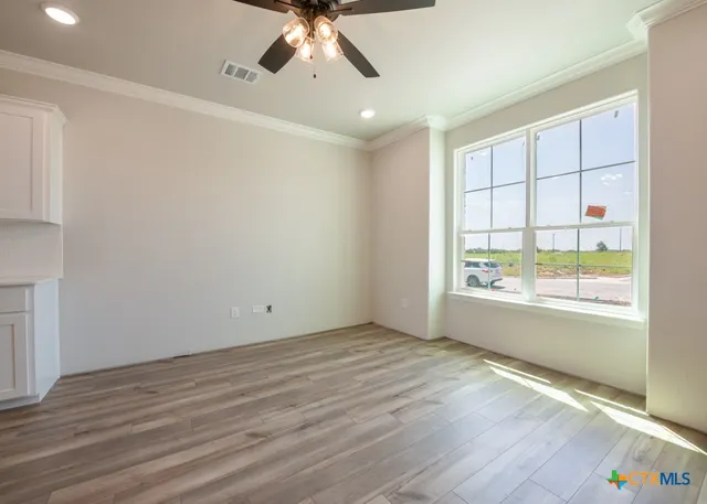 an empty room with wooden floor fan and windows