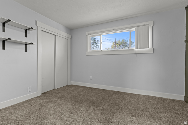 2101 West 3900th Street South Roy, UT 84067 - Photo 17 of 36 Carpeted room featuring a double-pane window, white baseboards, and a sliding closet door with white trim