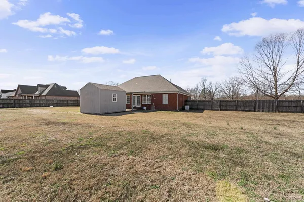a front view of house with yard and trees in the background
