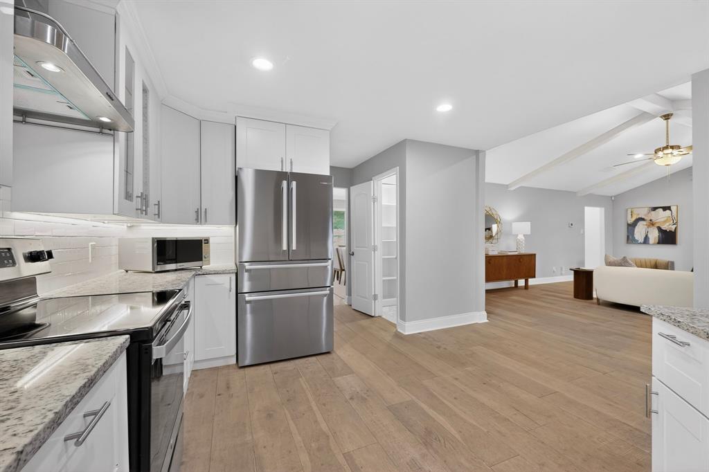 7631 Meadow Road Dallas, TX 75230 - Photo 12 of 40 Bright kitchen with sleek stainless steel appliances, rich hardwood floors and a pantry, blending functionality with elegance.