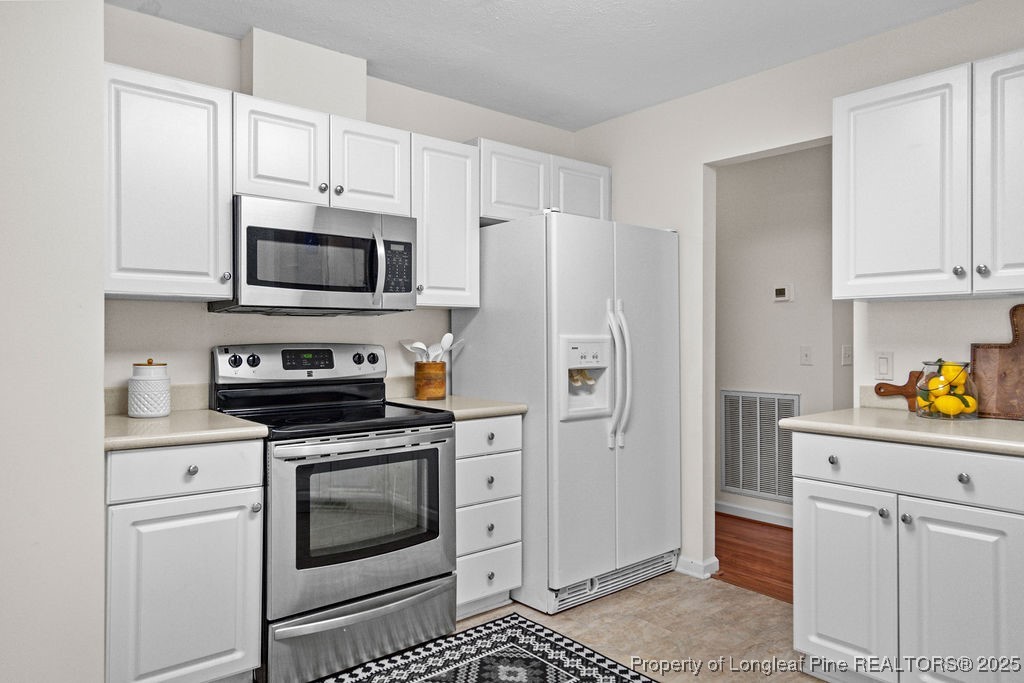 330 Fox Run Road Pinehurst, NC 28374 - Photo 13 of 31 a kitchen with white cabinets and stainless steel appliances