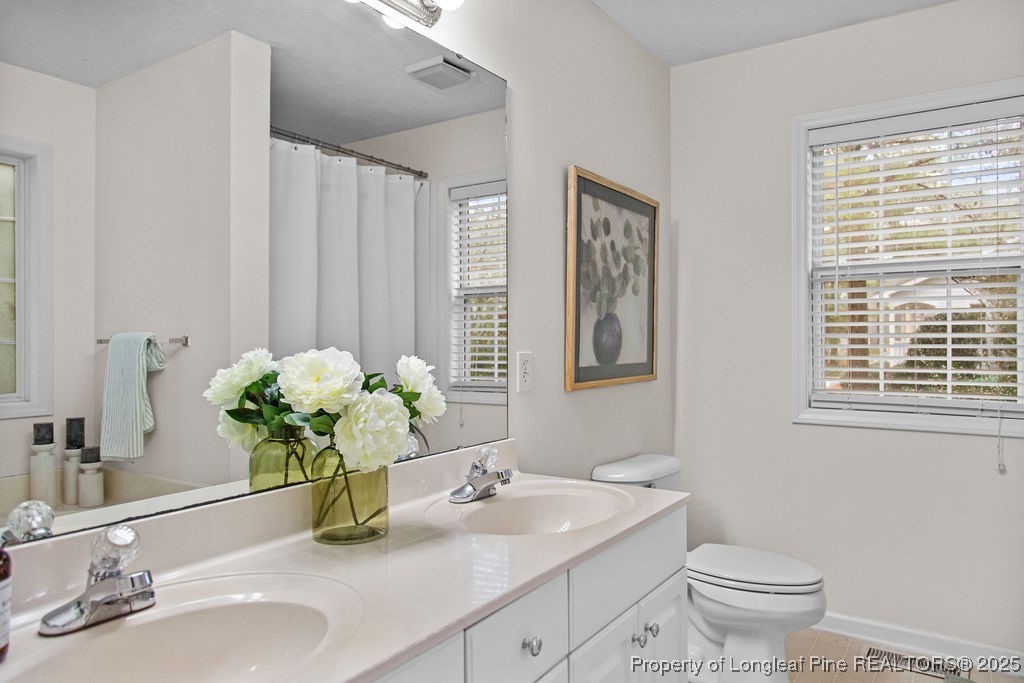 330 Fox Run Road Pinehurst, NC 28374 - Photo 23 of 31 a bathroom with a granite countertop sink a large mirror and a toilet