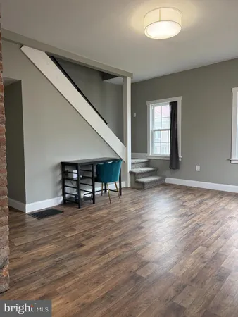 an empty room with wooden floor and lounge chair