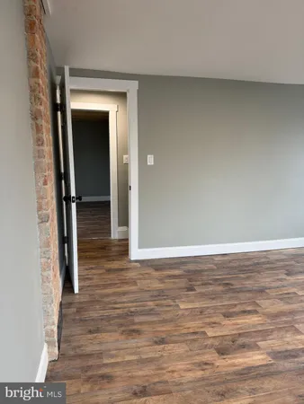 a view of empty room with wooden floor and wall