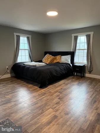 a spacious bedroom with a bed windows and wooden floor