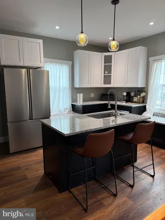 a kitchen with stainless steel appliances granite countertop wooden floors a stove a refrigerator and a microwave