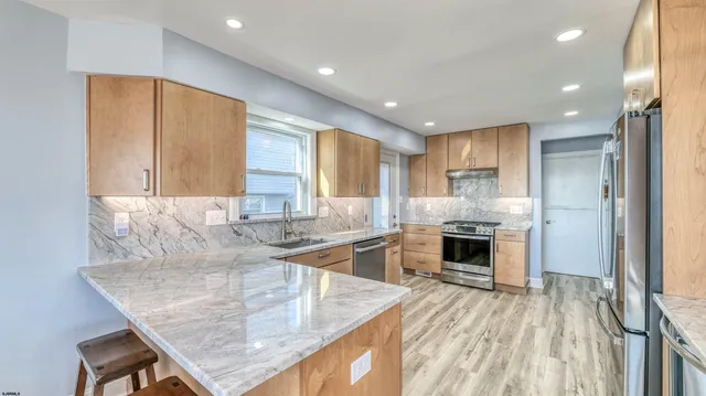 a kitchen with stainless steel appliances granite countertop a stove a sink and a refrigerator