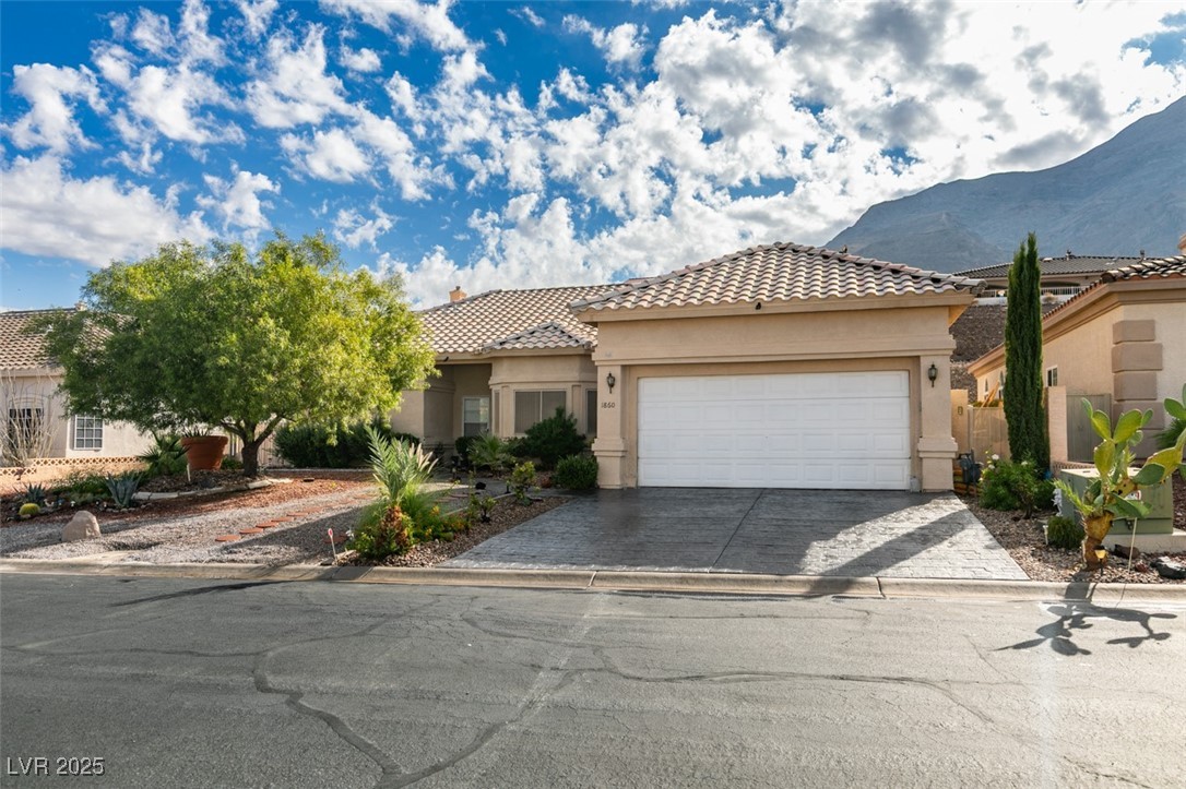 1860 Racine Drive Las Vegas, NV 89156 - Photo 35 of 36 Mediterranean / spanish house with stucco siding, a tile roof, decorative driveway, and a garage