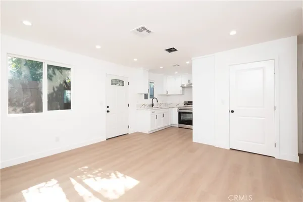 a view of a kitchen with a sink and dishwasher a refrigerator with wooden floor