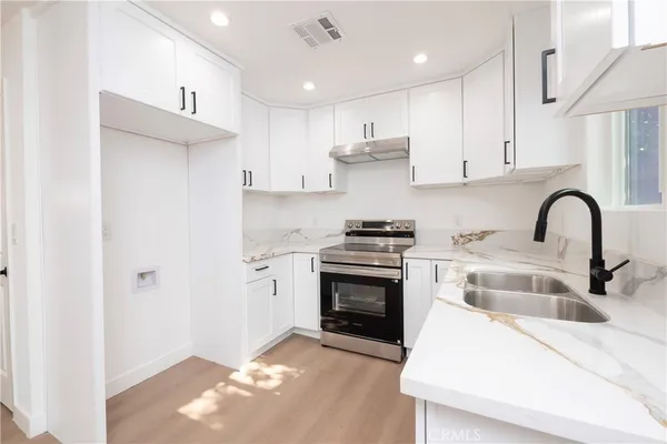 a kitchen with granite countertop a sink cabinets and stainless steel appliances