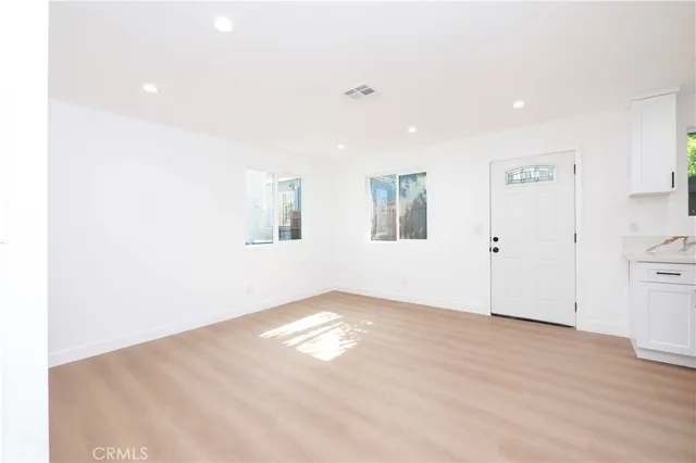 a view of empty room with wooden floor and window