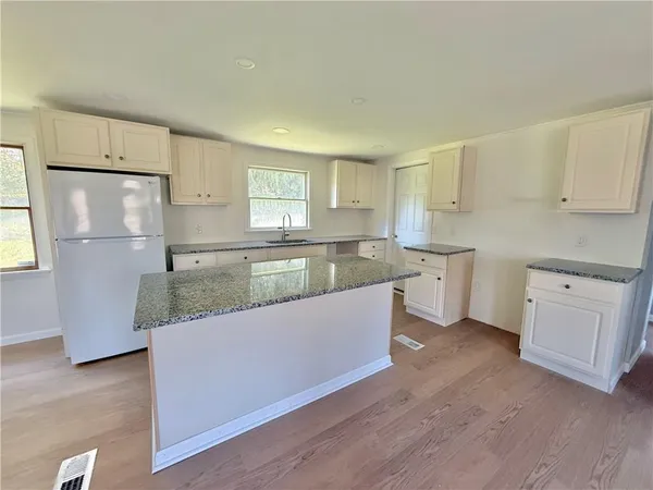 a large kitchen with white cabinets and wooden floors