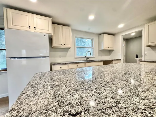 a kitchen with granite countertop a refrigerator and a sink