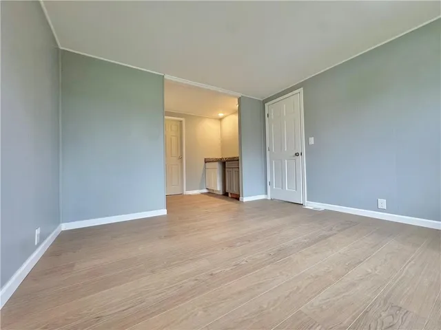 a view of an empty room with wooden floor and cabinets