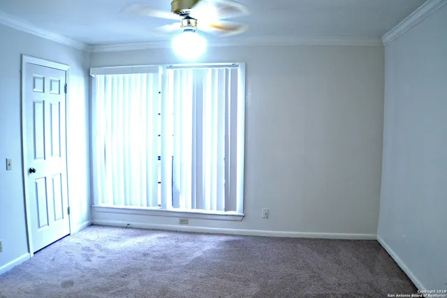 an empty room with windows and fan
