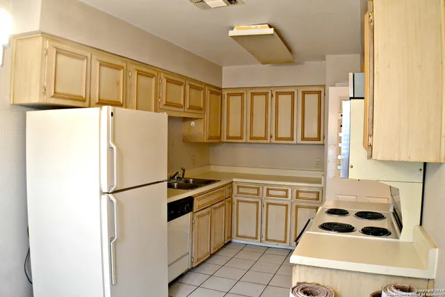 a kitchen with a refrigerator a sink and white cabinets