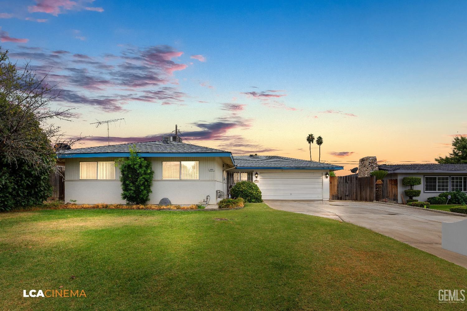 a front view of house with yard and trees in the background