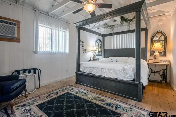 a bedroom with a bed next to a window with a chandelier