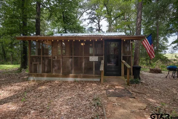 a view of a small house with a large window and wooden fence