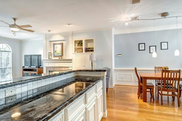a kitchen with granite countertop a stove a sink a dining table and chairs