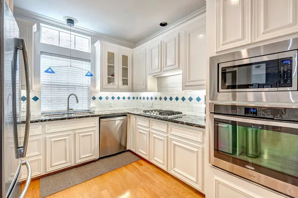 a kitchen with stainless steel appliances granite countertop a stove and white cabinets
