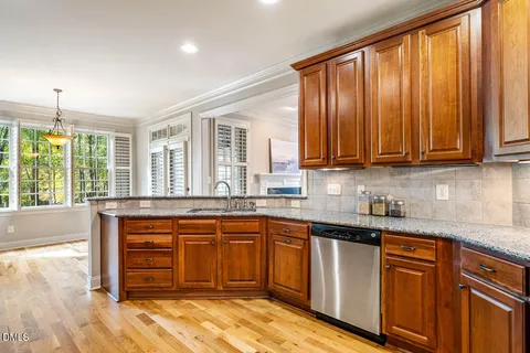 a kitchen with stainless steel appliances granite countertop wooden cabinets a sink and dishwasher with wooden floor