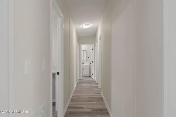 a view of a hallway with wooden floor and a bathroom