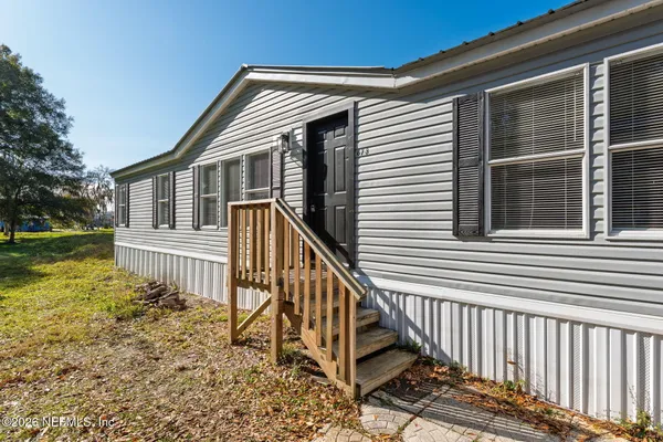 a view of a house with wooden fence next to a yard
