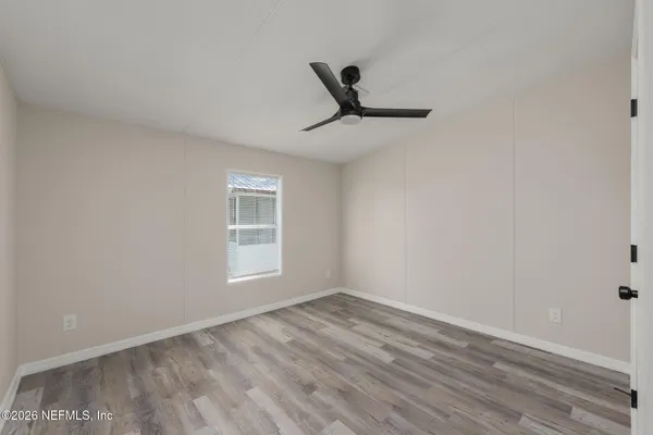 a view of empty room with wooden floor and fan