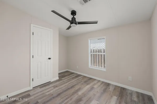 a view of empty room with wooden floor and fan