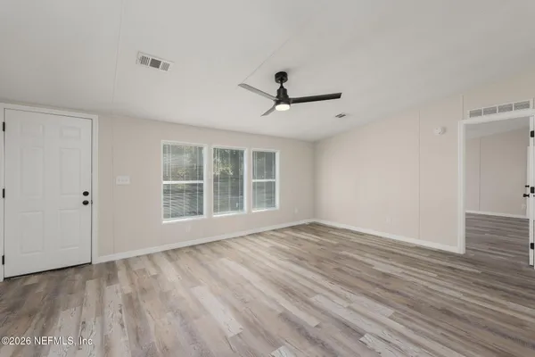 a view of an empty room with wooden floor and a window