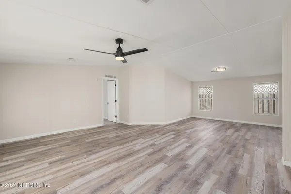 a view of empty room with wooden floor and fan