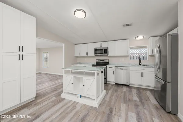 a kitchen with white cabinets and stainless steel appliances