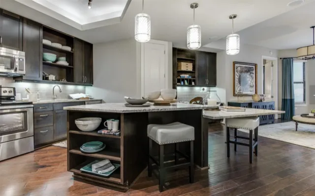 a kitchen with granite countertop a stove a sink dining table and chairs with wooden floor