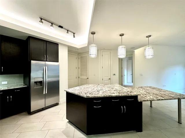 a kitchen with granite countertop kitchen island stainless steel appliances a sink stove and refrigerator