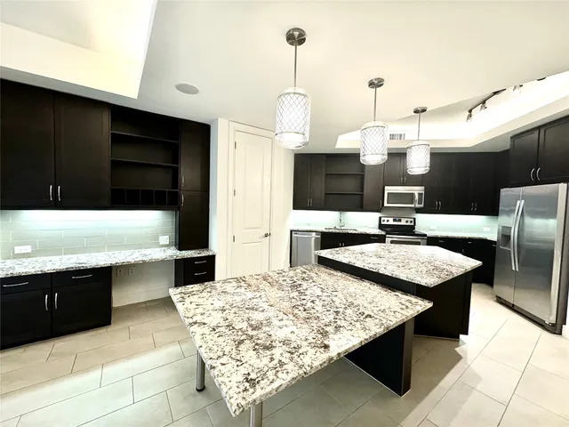 a kitchen with stainless steel appliances kitchen island granite countertop a sink counter and chairs