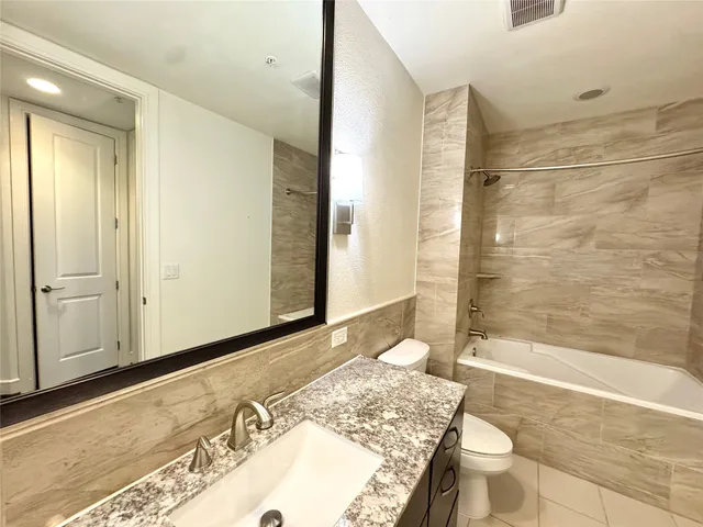a bathroom with a double vanity sink toilet mirror and bathtub