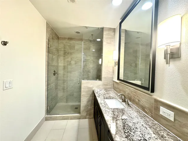a bathroom with a granite countertop bathtub shower sink and mirror