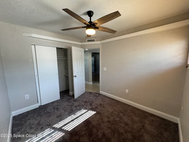 an empty room with closet and a ceiling fan