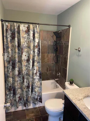 a bathroom with a granite countertop sink toilet and shower