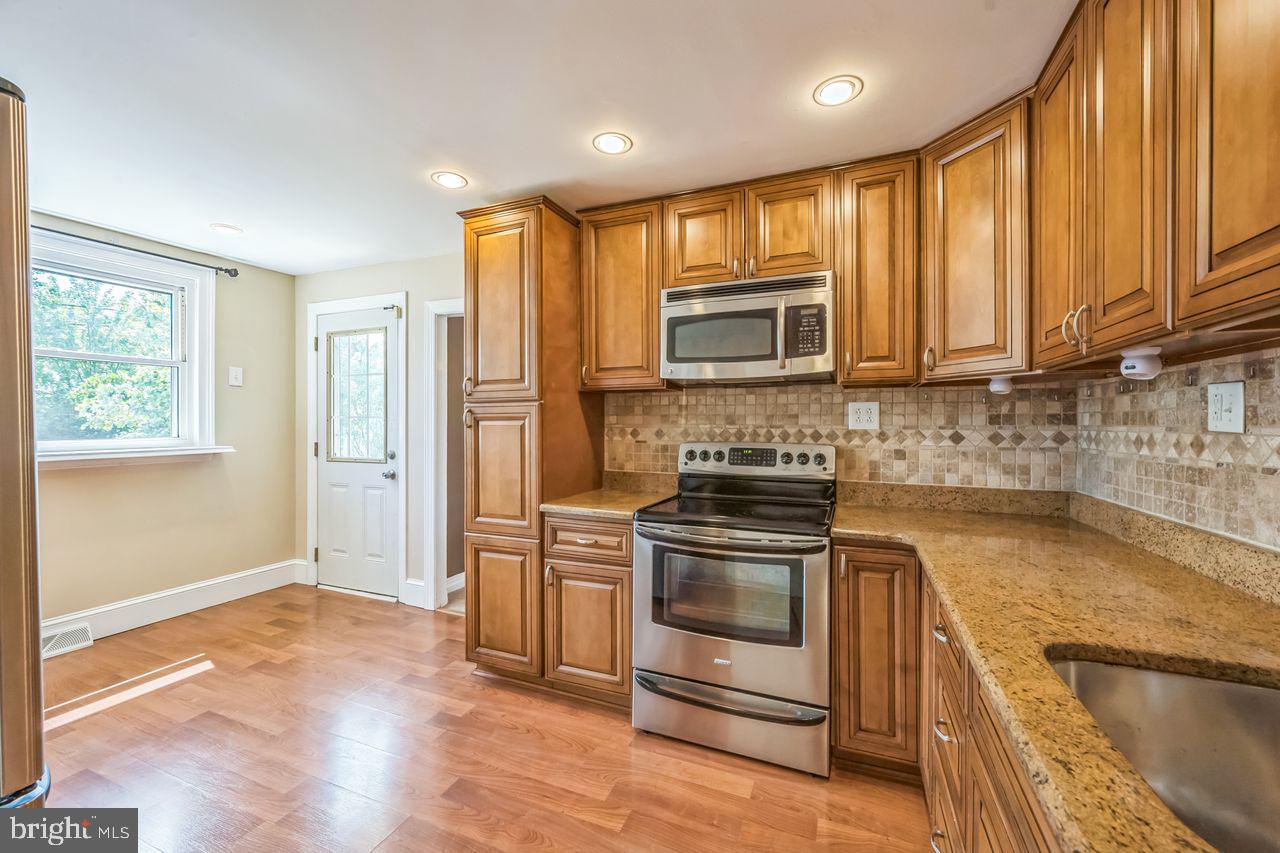 9731 Glenhope Road Philadelphia, PA 19115 - Photo 11 of 36 a kitchen with granite countertop wooden cabinets stainless steel appliances and a window