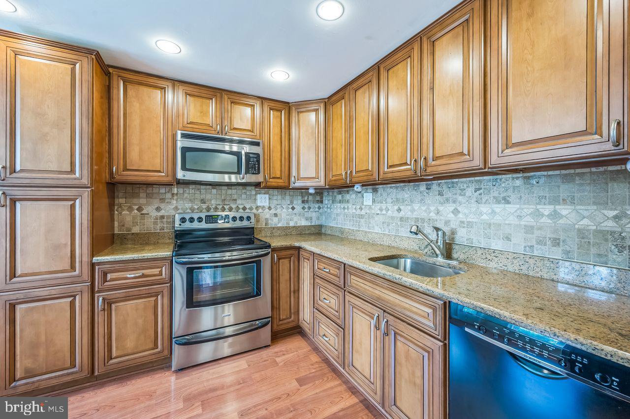 9731 Glenhope Road Philadelphia, PA 19115 - Photo 13 of 36 a kitchen with stainless steel appliances granite countertop a stove a sink and a microwave