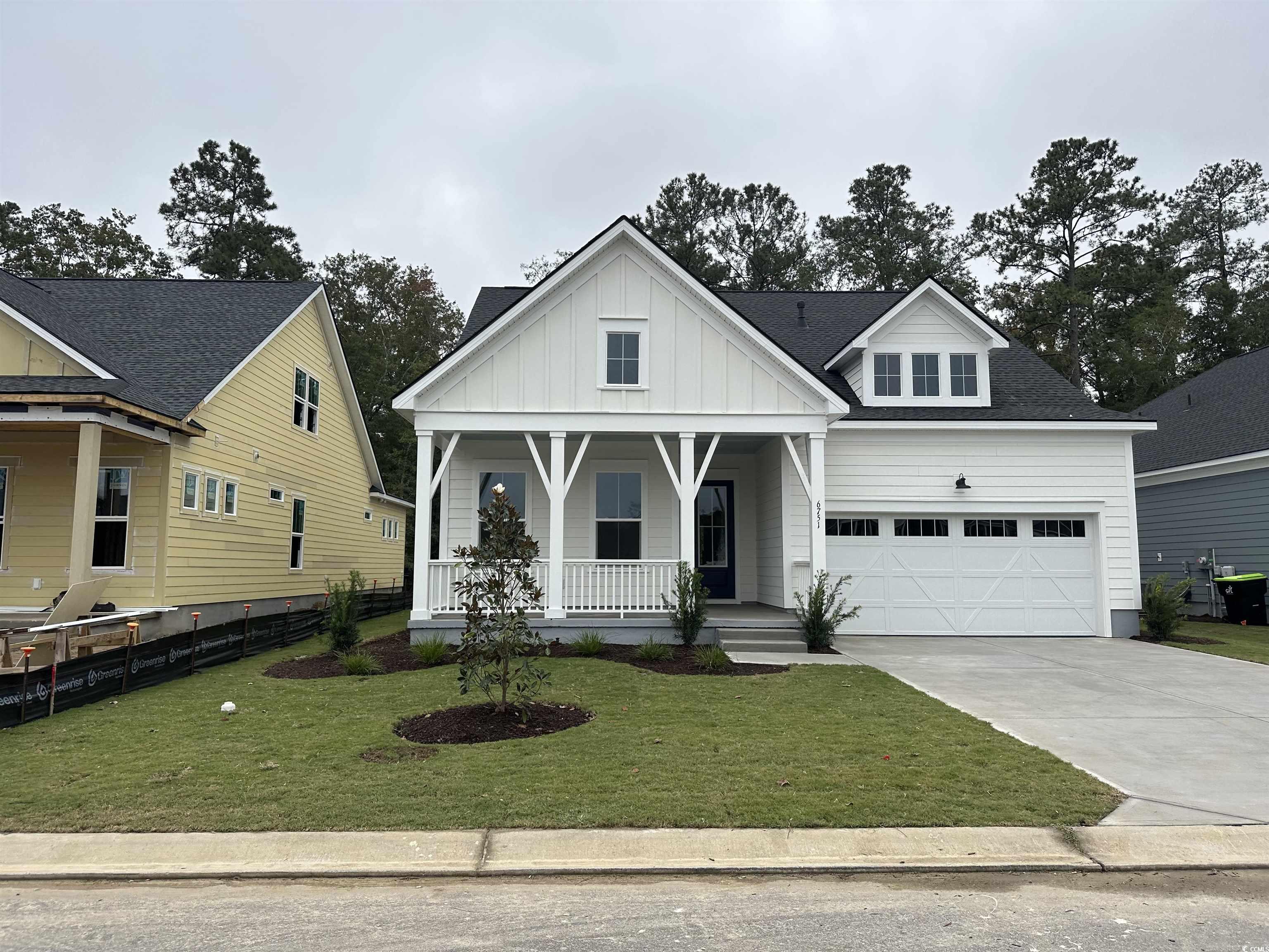 6751 Genesis Drive Murrells Inlet, SC 29576 - Photo 1 of 1 Modern farmhouse style home with a front yard, covered porch, board and batten siding, a shingled roof, and a garage