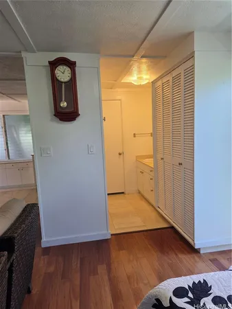an empty room with wooden floor and a way to kitchen