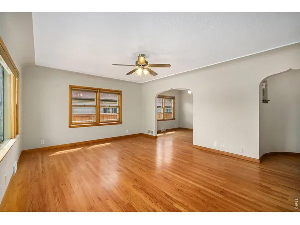 a view of an empty room with window and wooden floor