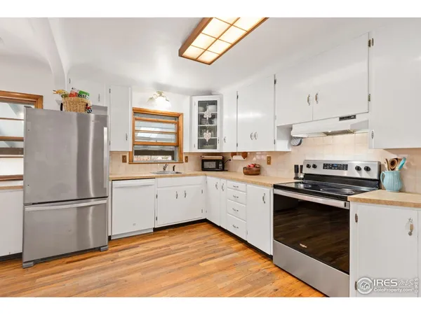 a kitchen with stainless steel appliances granite countertop a refrigerator a stove a sink and white cabinets