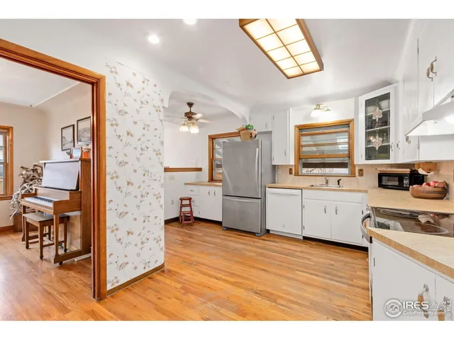 a kitchen with stainless steel appliances a stove top oven a refrigerator a sink dishwasher with wooden floor and cabinets